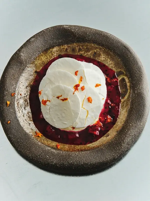 Thin meringue discs over a berry compote
