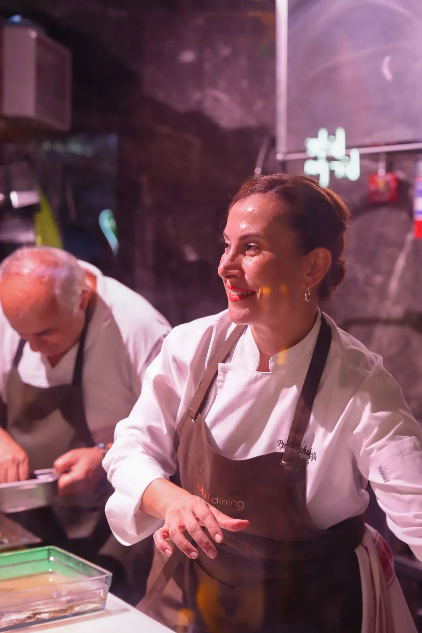 Pınar İshakoğlu smiling as she serves from an open kitchen