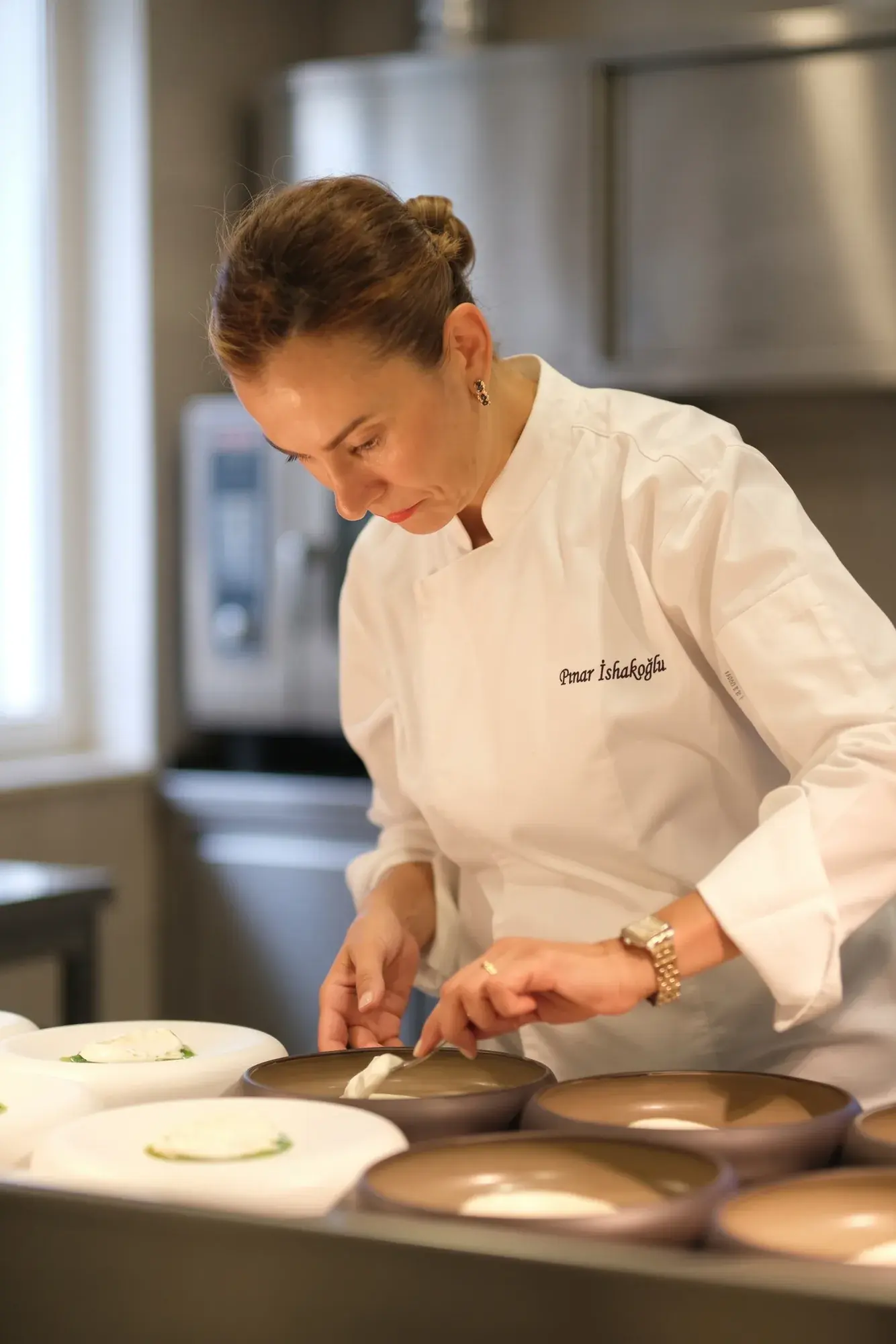 Pınar İshakoğlu placing burrata into bowls in the kitchen